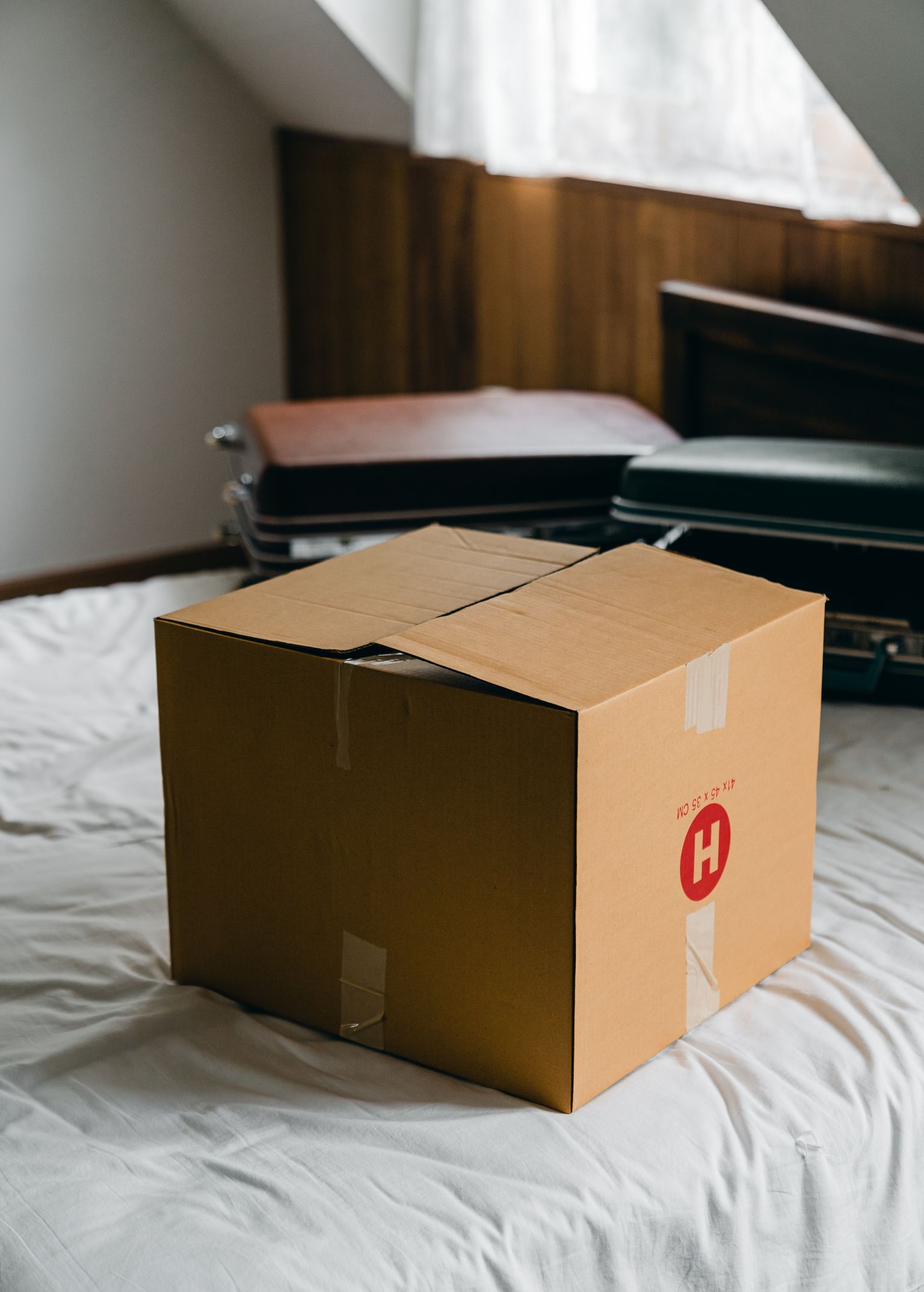 Moving box and luggage photographed in a small bedroom